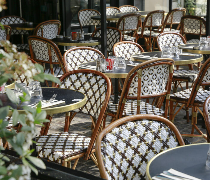 Terrasse parisienne avec chaises en rotin et guéridons